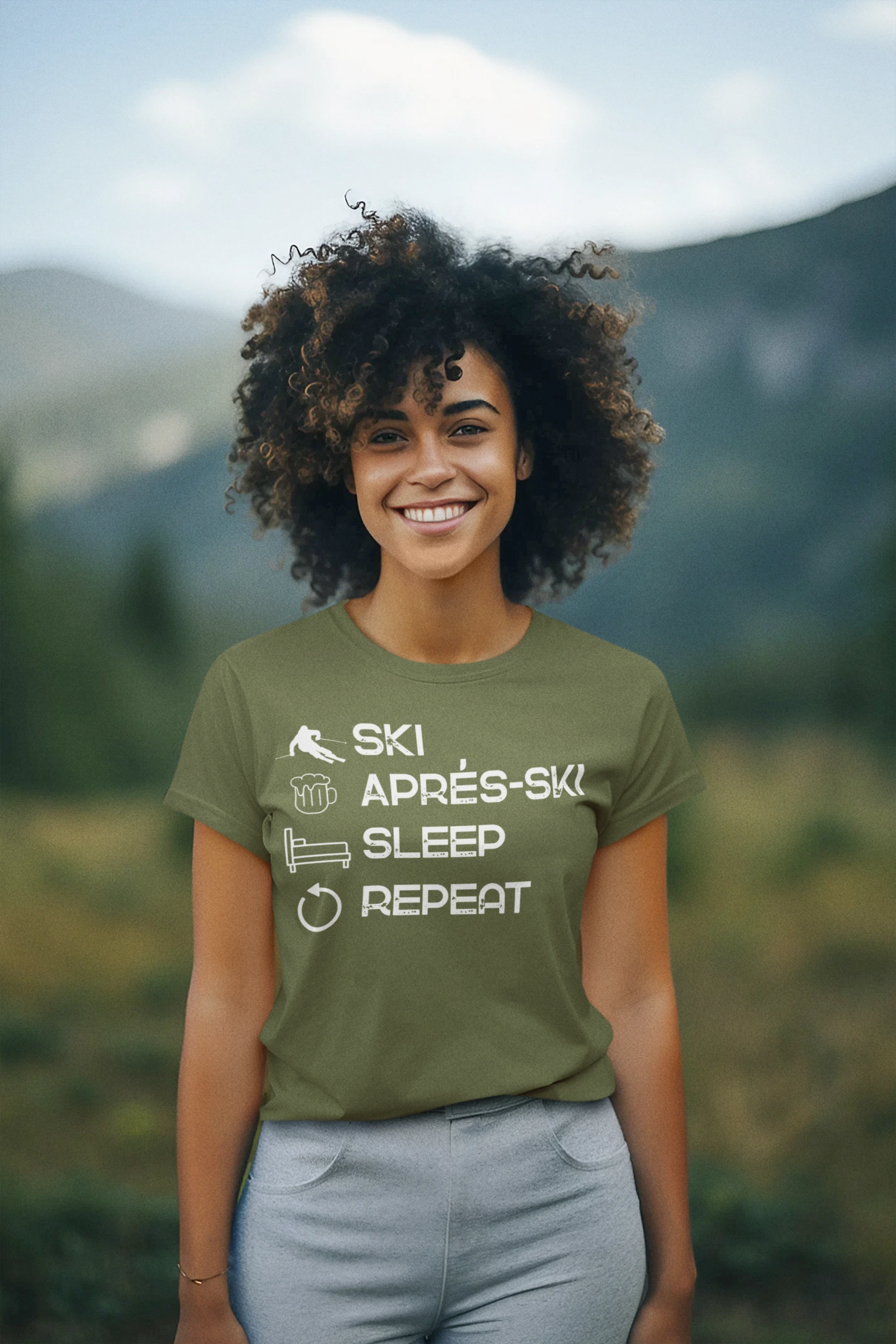 Person wearing a green t-shirt with text in a mountainous landscape