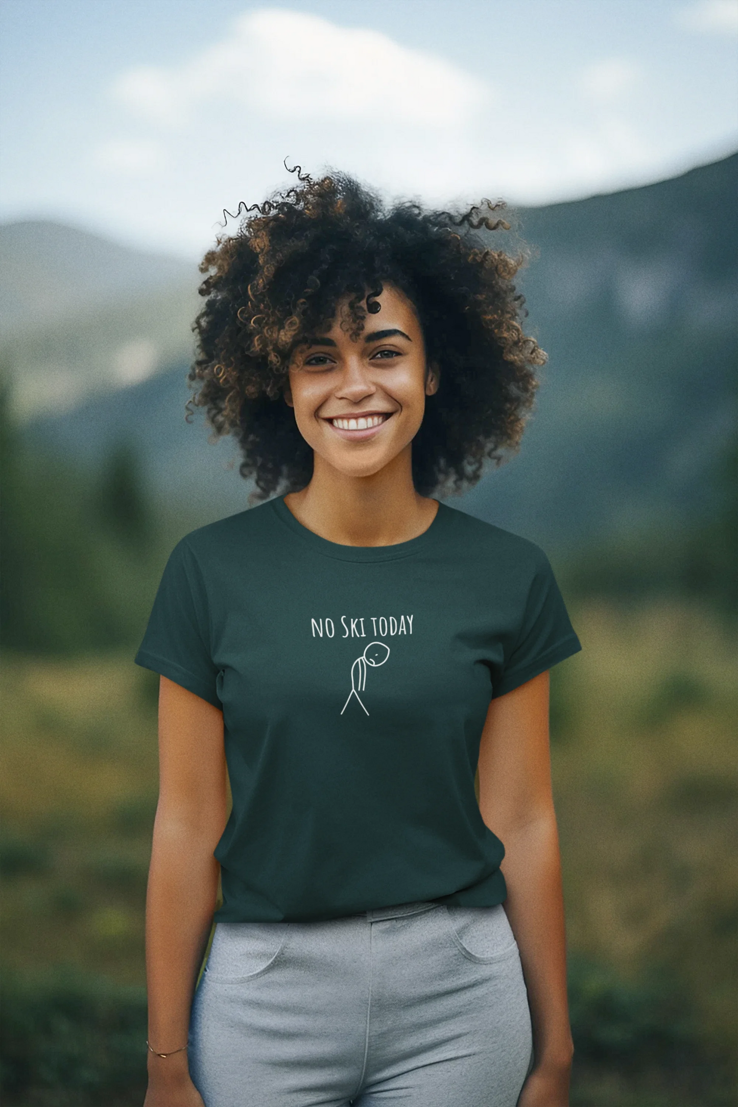 Person wearing a green t-shirt with 'No Ski Today' text in a mountainous landscape