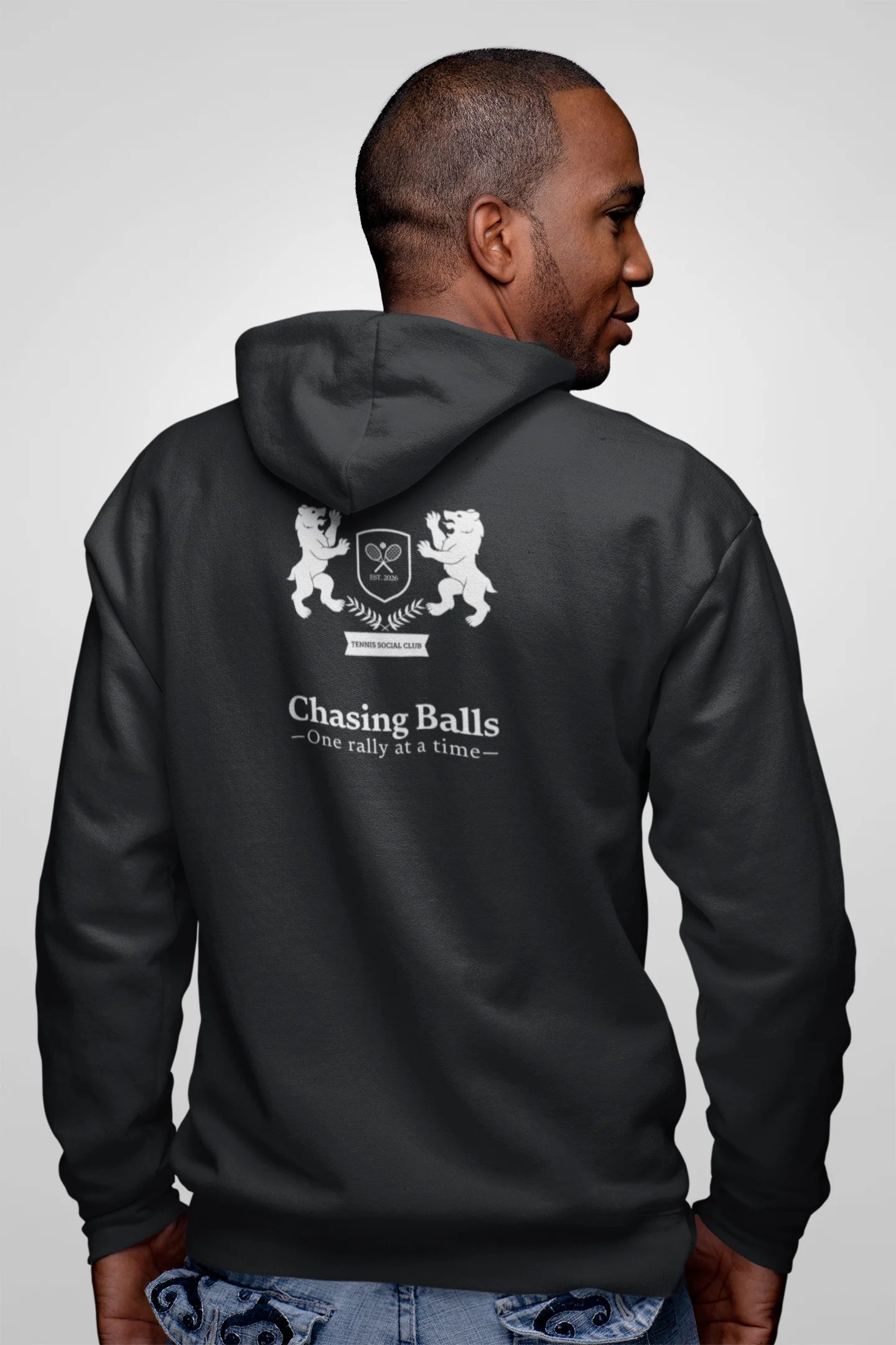 Person wearing a black hoodie with a graphic design on the back against a plain background