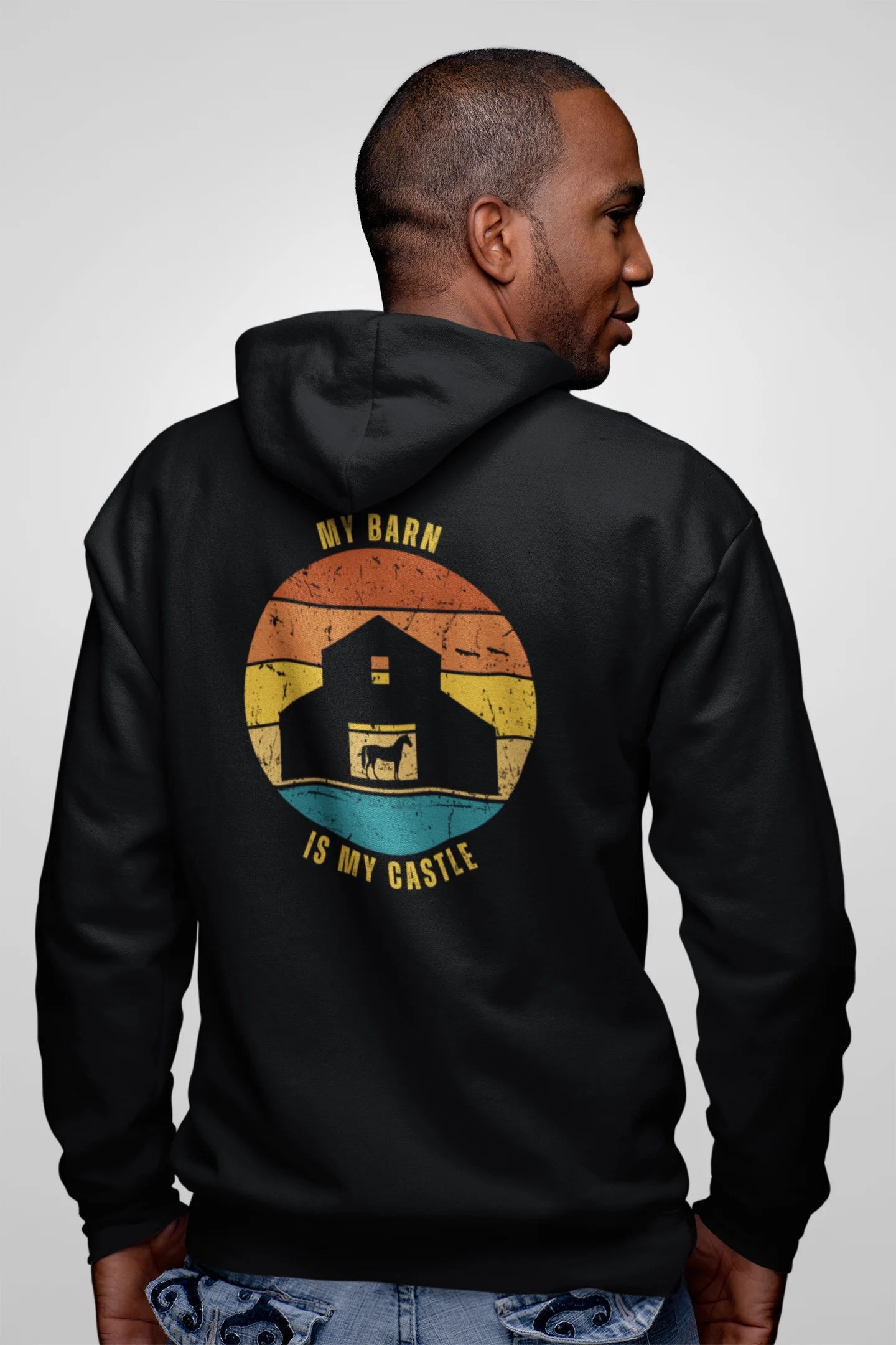 Equestrian Hoodie with Stable Hair Don't Care text and horse barn back print. Person wearing a black hoodie with a graphic design on the back, featuring a barn and text, against a plain background.