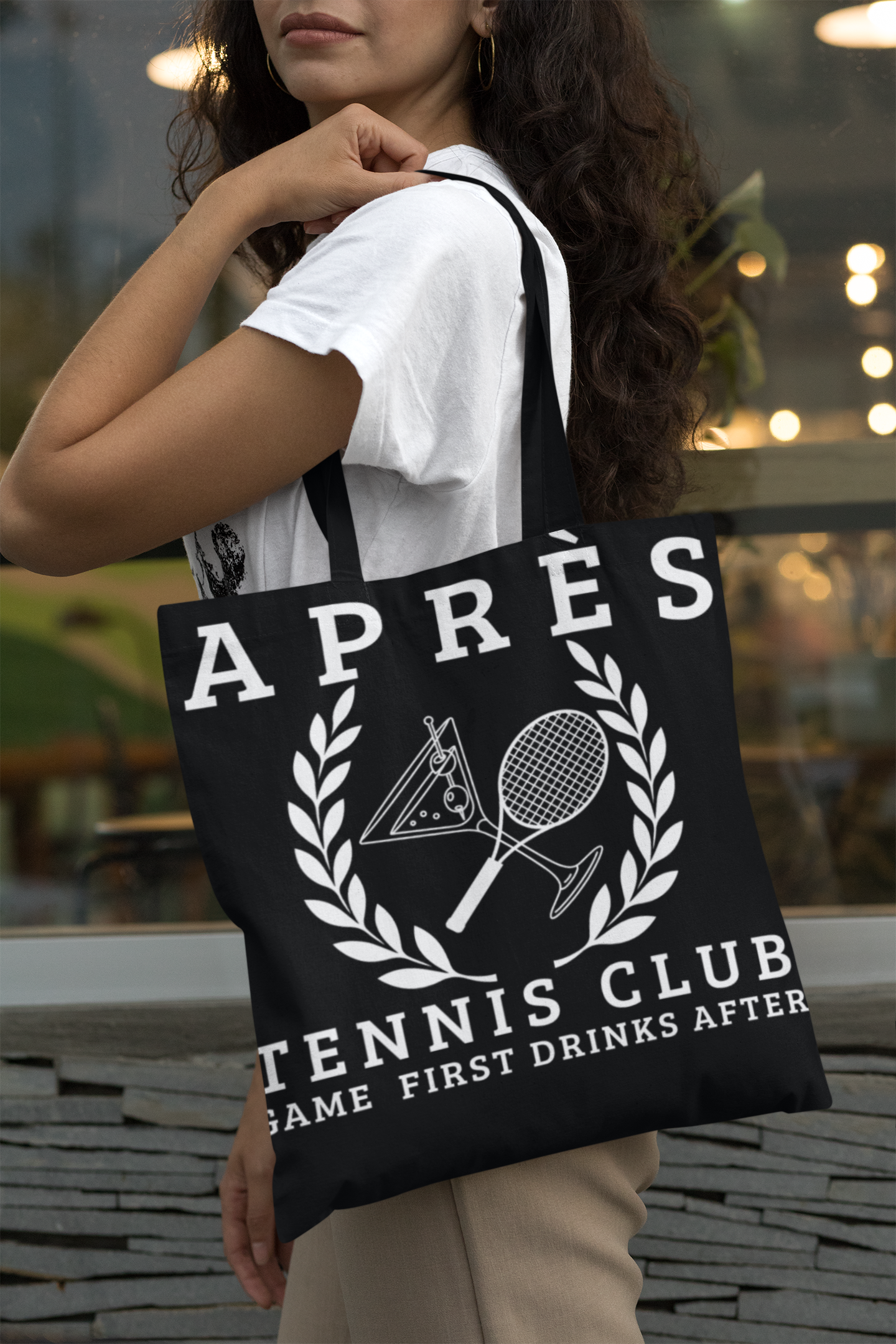 tennis tote bag Person holding a tote bag with 'Ap
es Tennis Club' design.