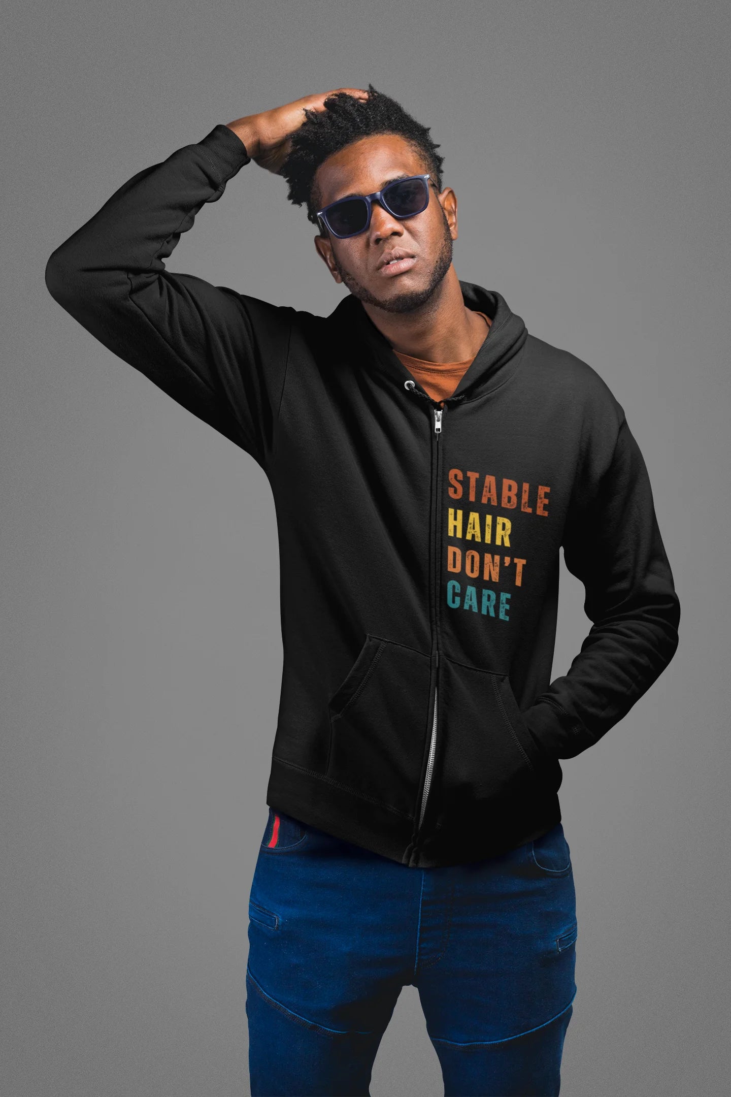 Equestrian Hoodie with Stable Hair Don't Care text and horse barn back print. Man wearing a black hoodie with colorful text on a gray background