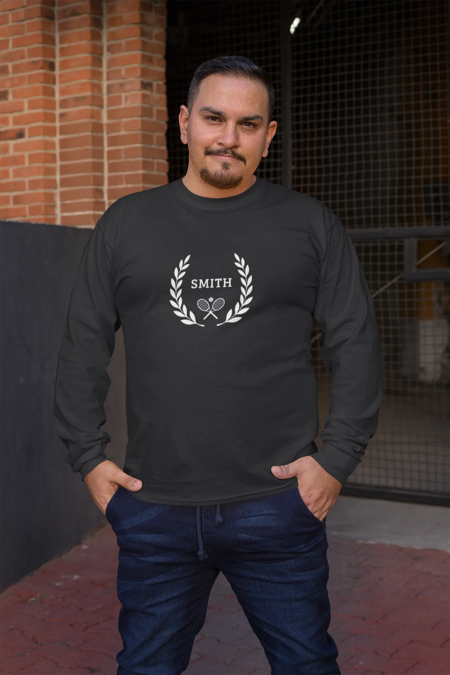 long sleeve tennis shirt Man wearing a black long-sleeve shirt with 'Smith' logo standing in front of a brick wall.