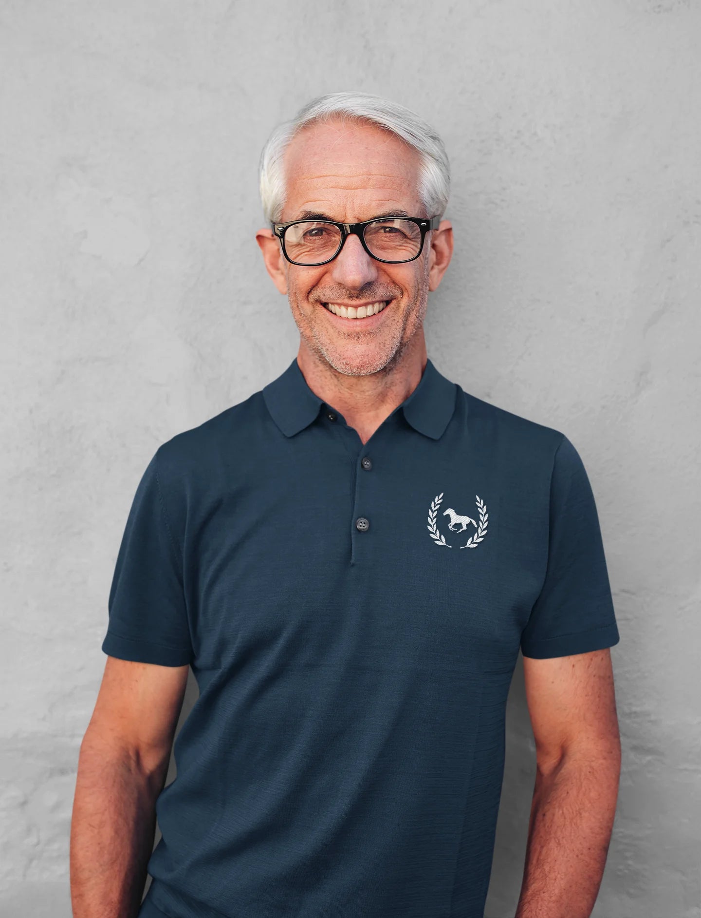 Man wearing a navy polo shirt with a logo against a gray background