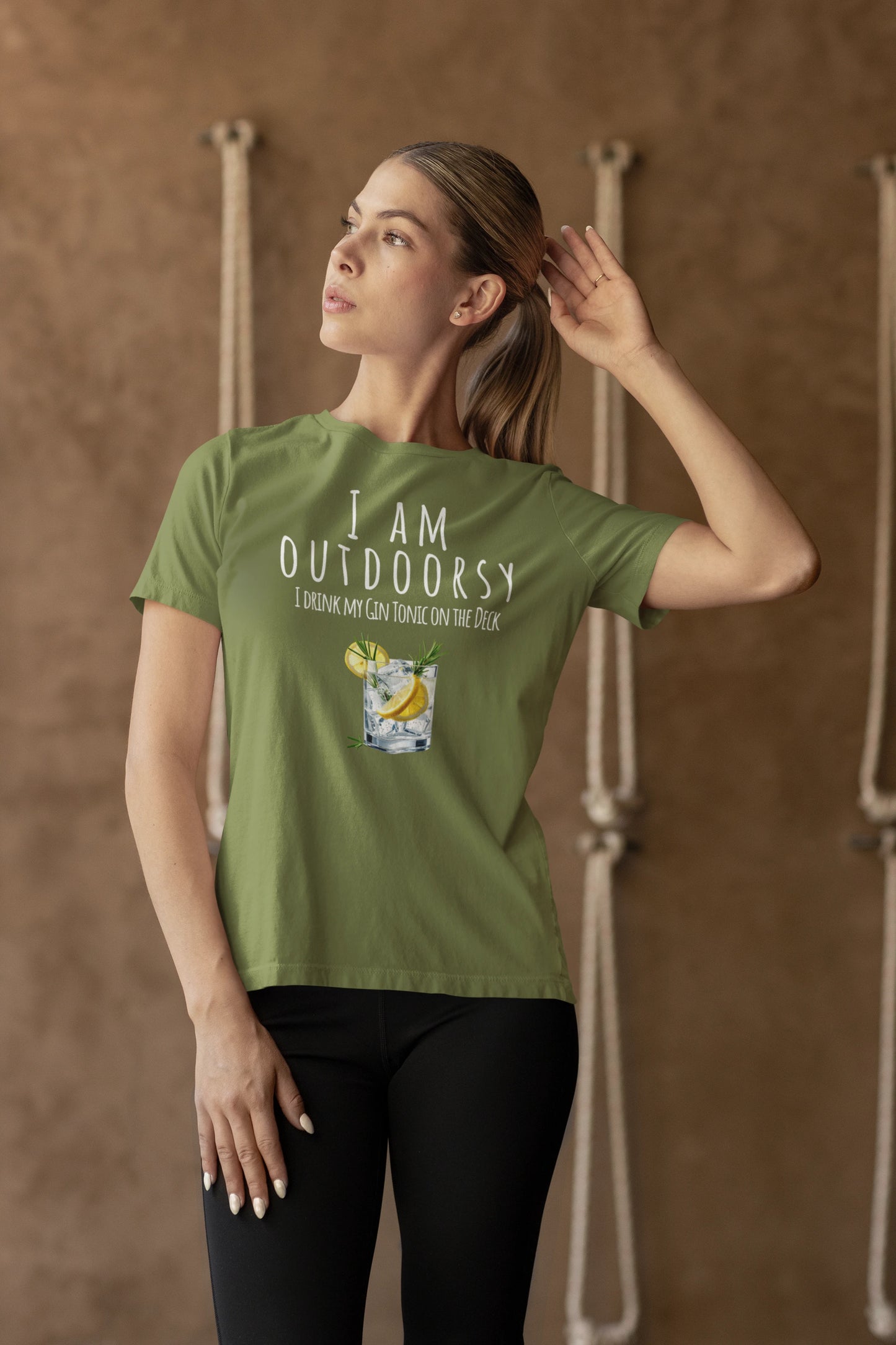 Woman wearing a green t-shirt with text and graphic, standing against a brown background.