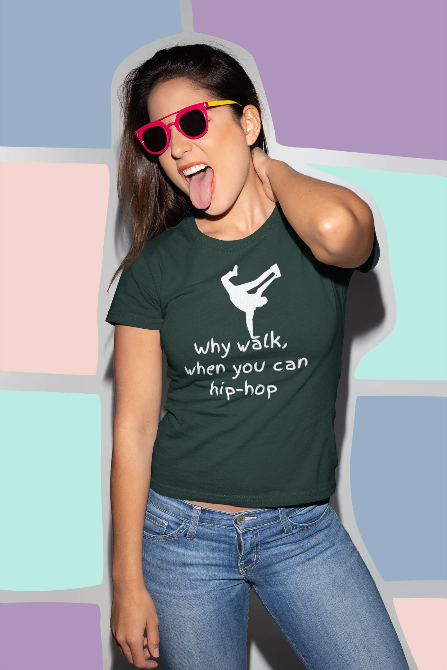 Person wearing a green t-shirt with a graphic and text, standing against a colorful geometric-patterned wall.