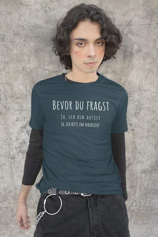 Person wearing a teal t-shirt with text against a textured wall background