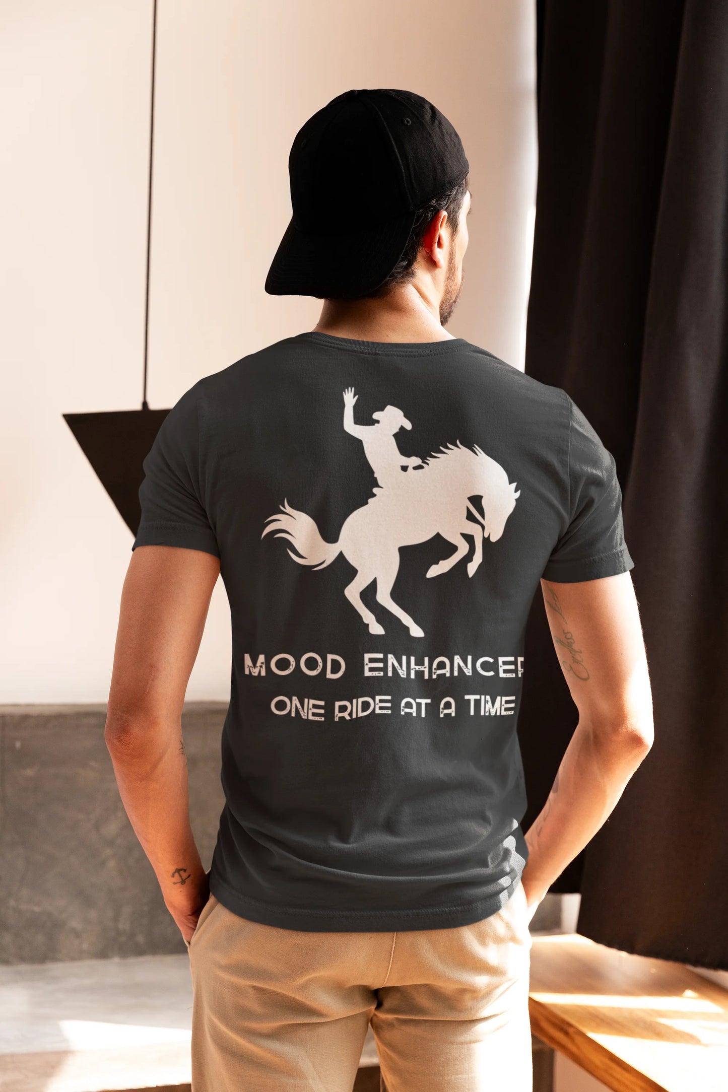 Person wearing a black t-shirt with a graphic and text, standing indoors.
