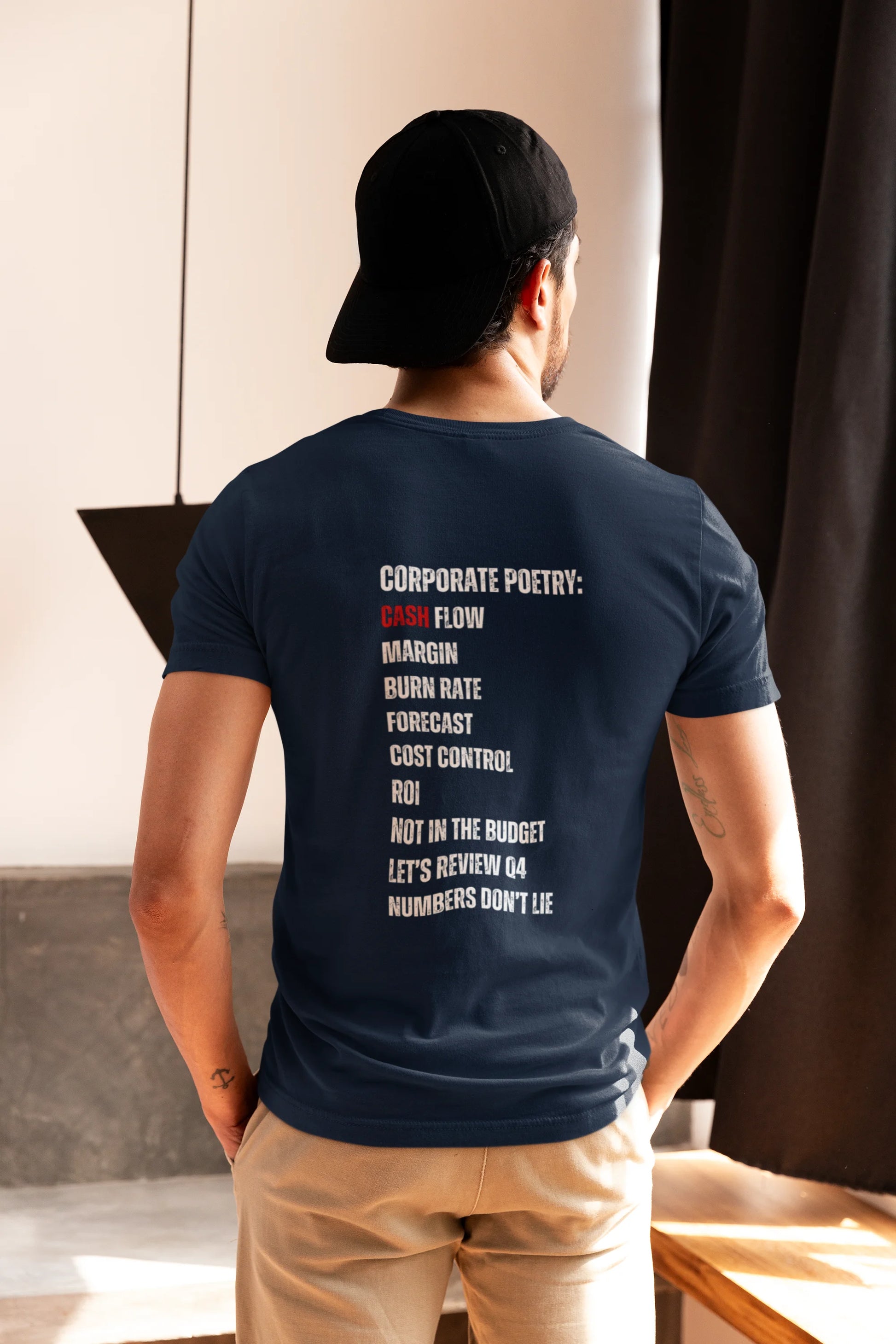 Finance Manager Shirt Person wearing a navy blue t-shirt with text on the back, standing indoors.