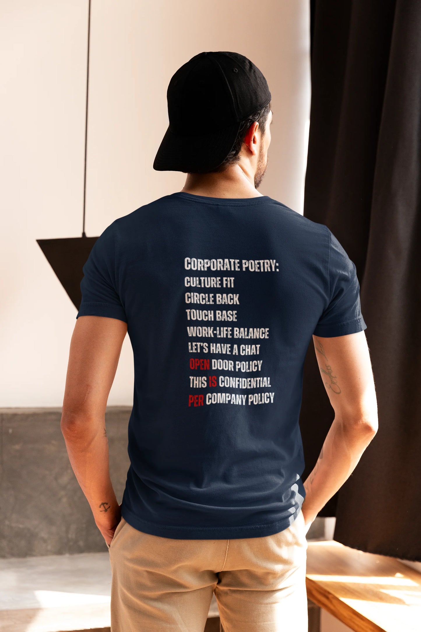 I love my Job T-Shirt Man wearing a navy blue t-shirt with text on the back, standing indoors.