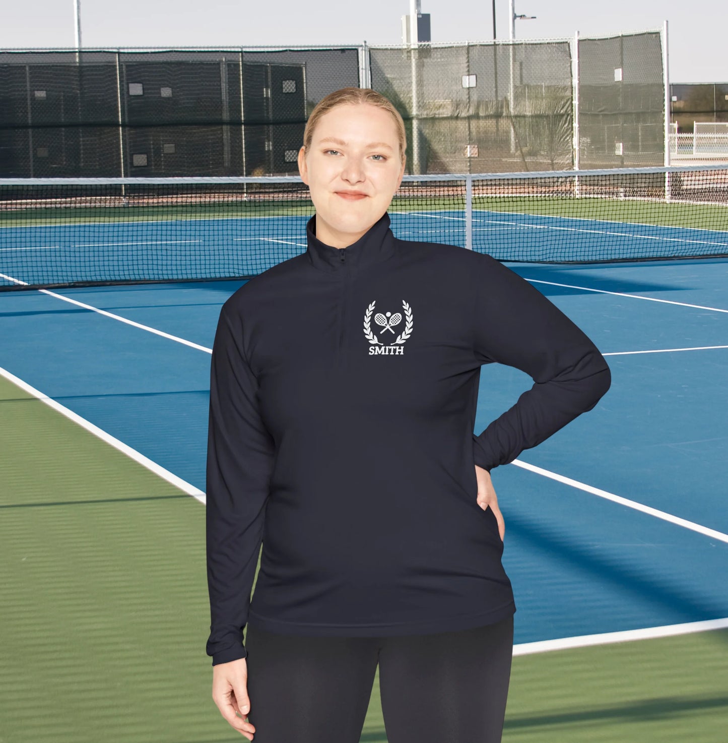 Personalized tennis racket sweater Person wearing a black long-sleeve shirt with a logo on a tennis court