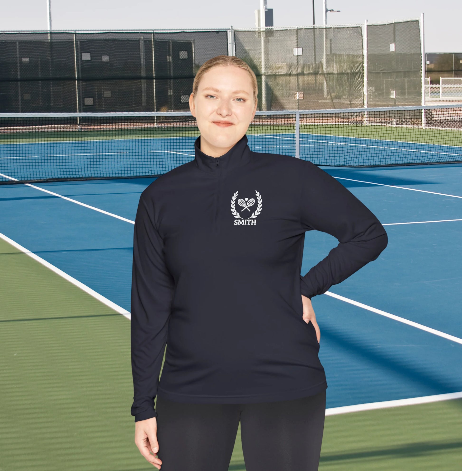 Personalized tennis racket sweater Person wearing a black long-sleeve shirt with a logo on a tennis court