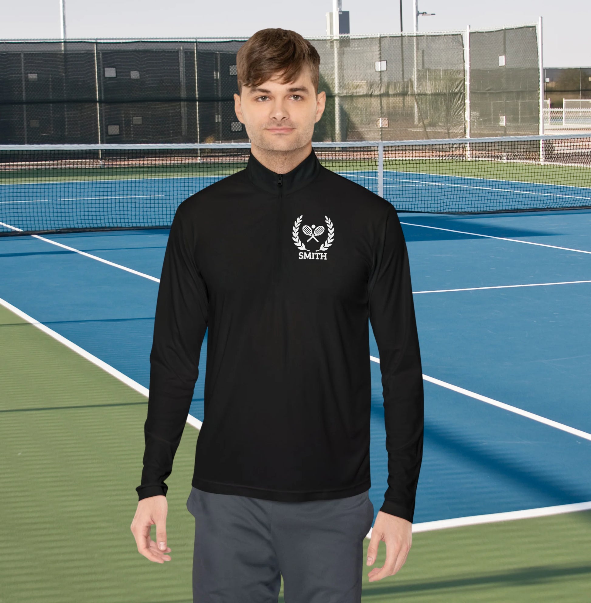 Personalized tennis racket sweater Man wearing a black athletic jacket with a logo on a tennis court
