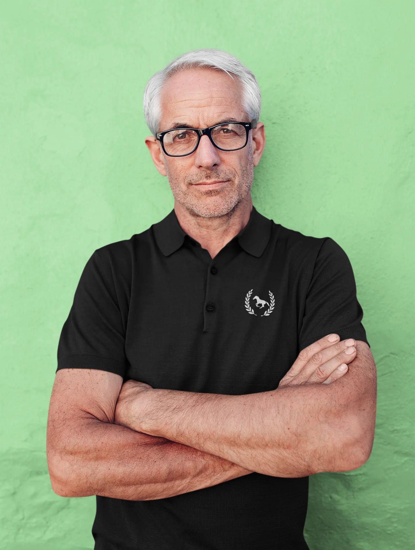 Man wearing a black polo shirt with a logo against a green background