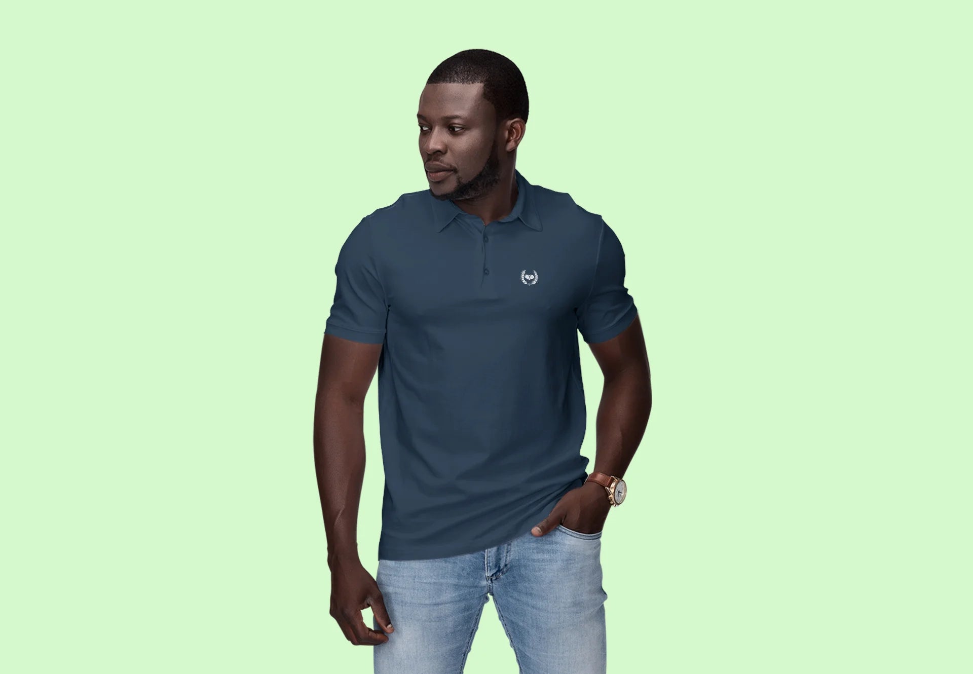 Man wearing a navy blue polo shirt with a logo on a light green background