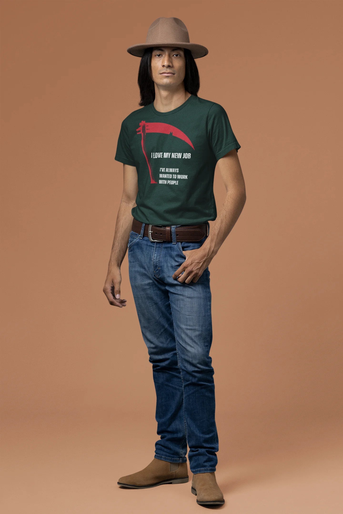 Man wearing a green t-shirt with a graphic design, blue jeans, and a brown hat on a brown background