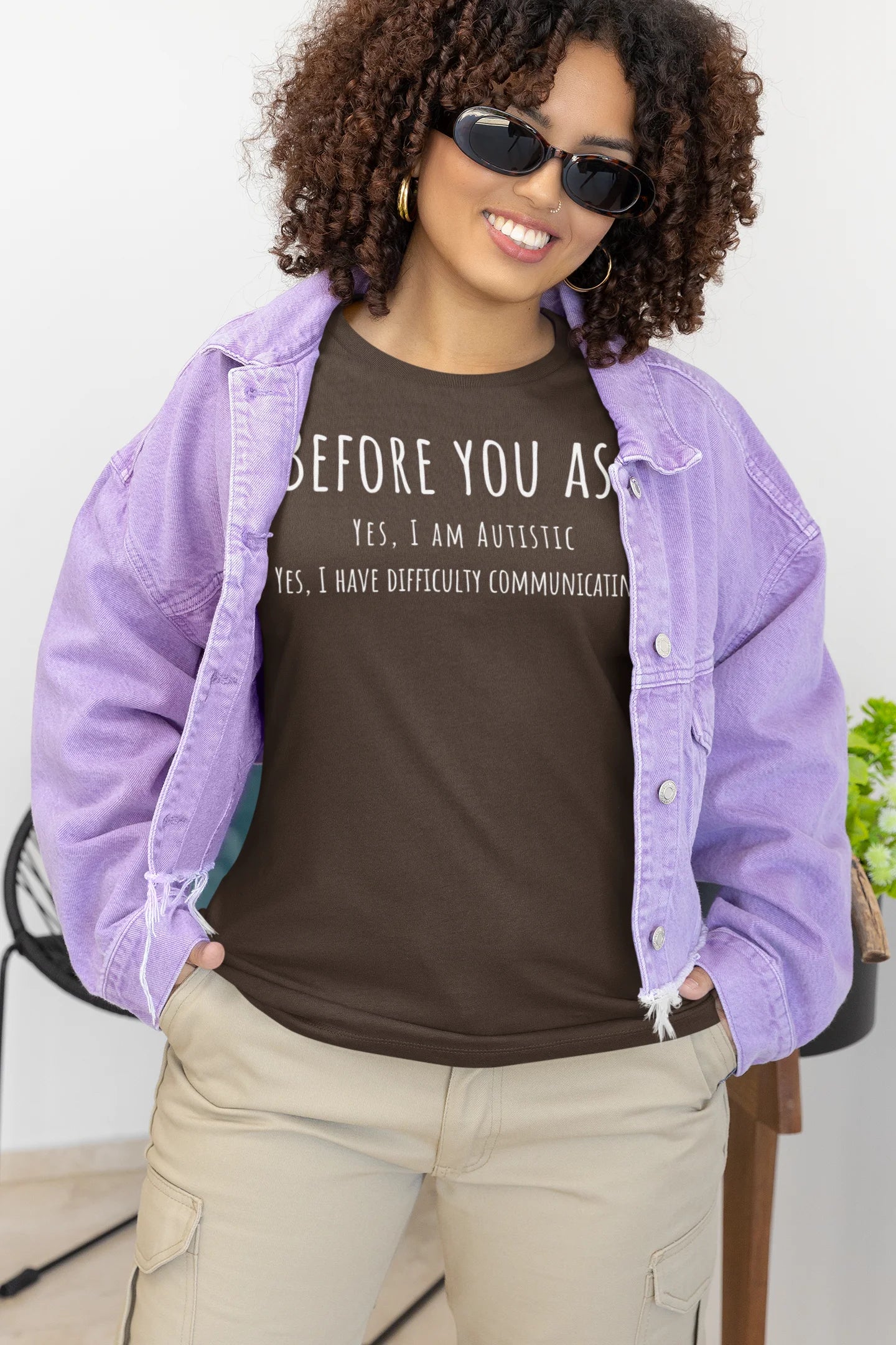 Person wearing a purple jacket over a brown t-shirt with text, standing indoors.
