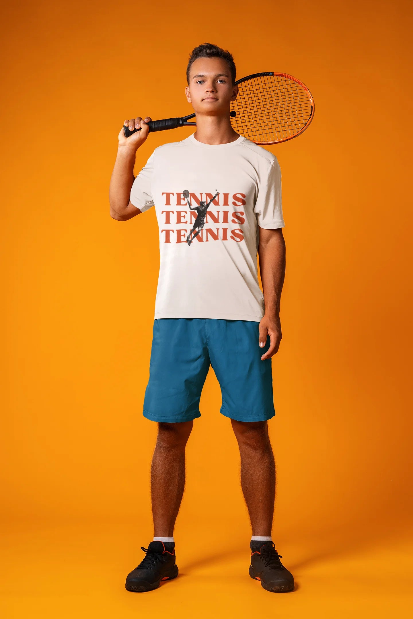 Person holding a tennis racket wearing a 'Tennis' t-shirt and blue shorts on an orange background