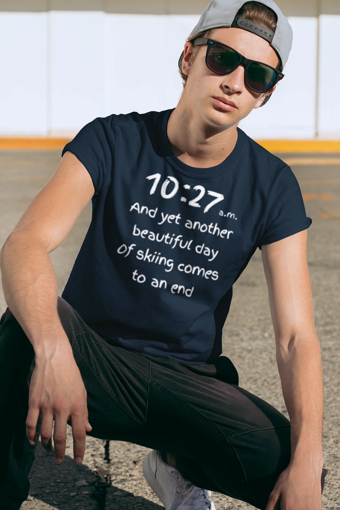Person wearing a navy blue t-shirt with text, sitting outdoors.