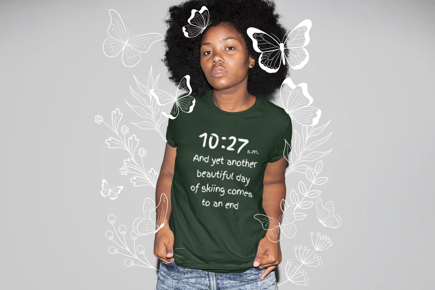 Person wearing a green t-shirt with text, standing against a gray background with butterfly graphics.