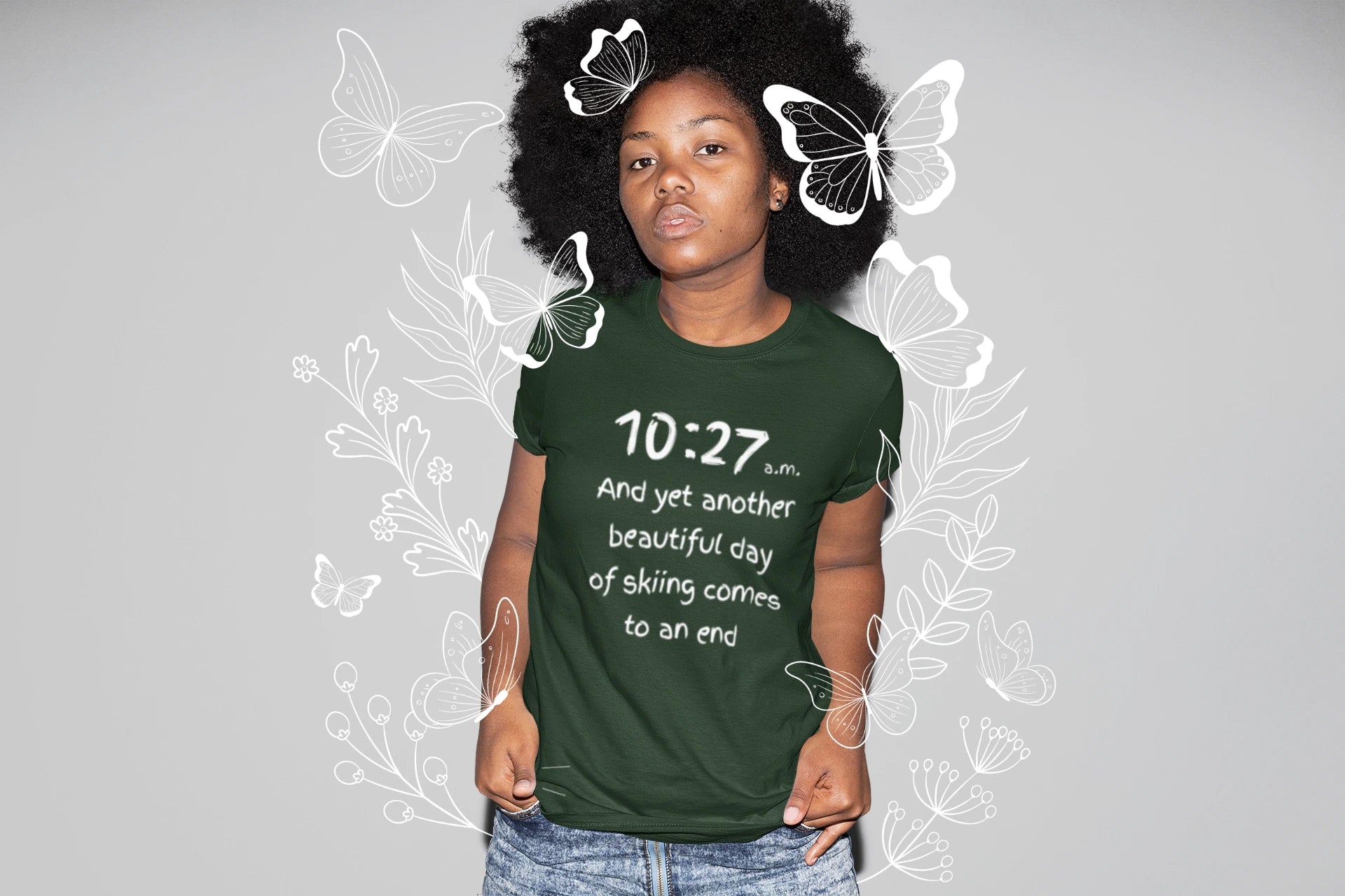 Person wearing a green t-shirt with text, standing against a gray background with butterfly graphics.