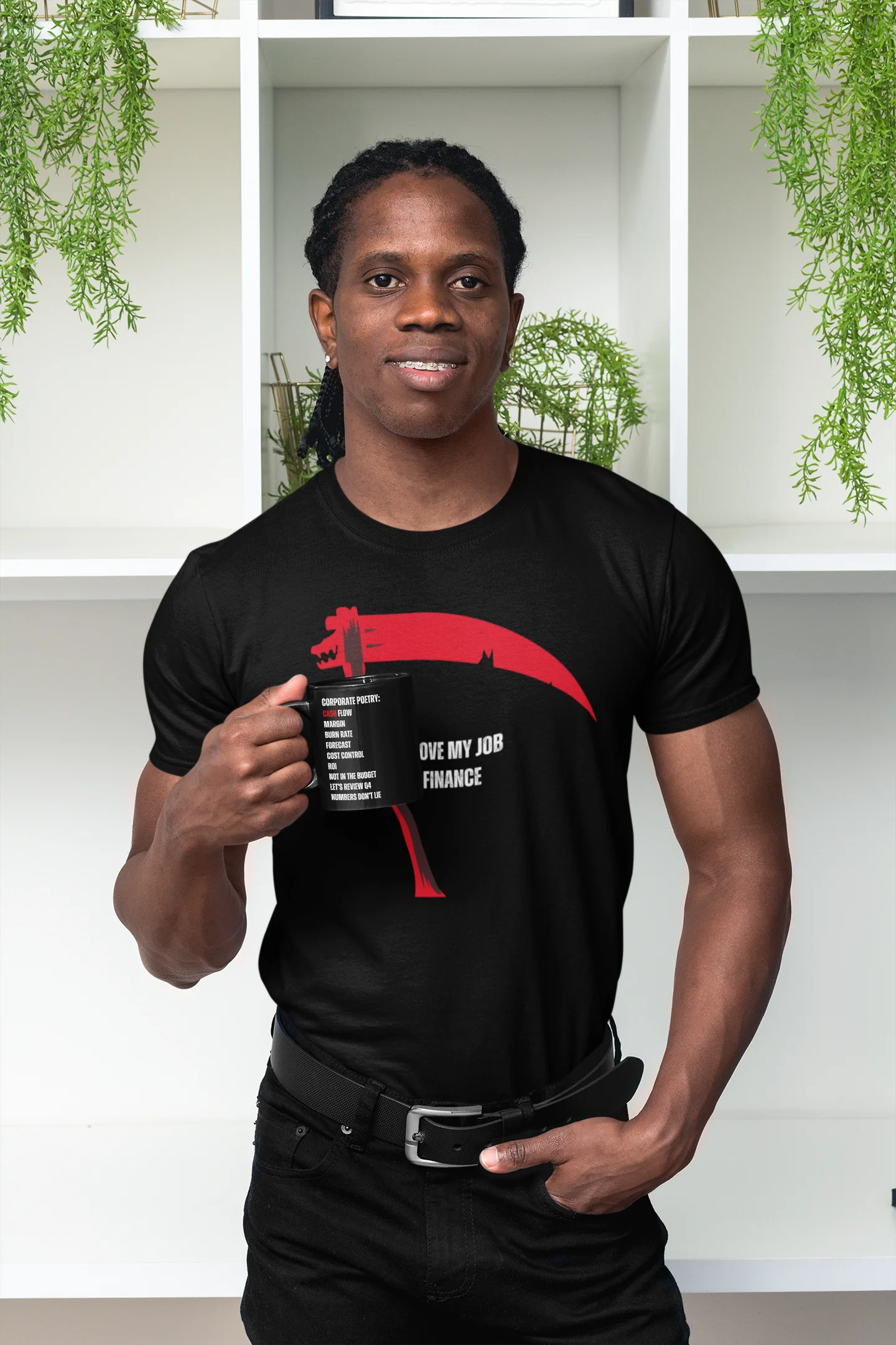 Person wearing a black t-shirt with a graphic design, holding a mug indoors.