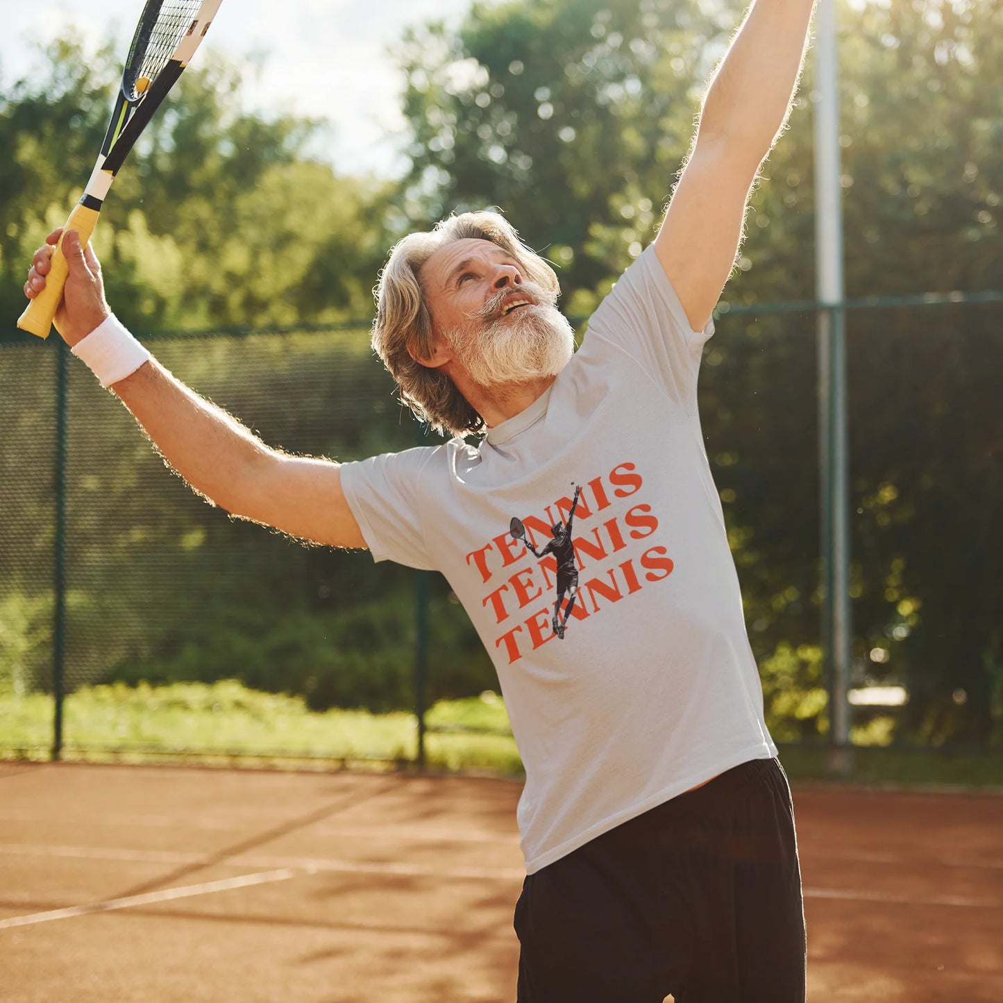 Man playing tennis on a court wearing a t-shirt with 'Tennis' text.