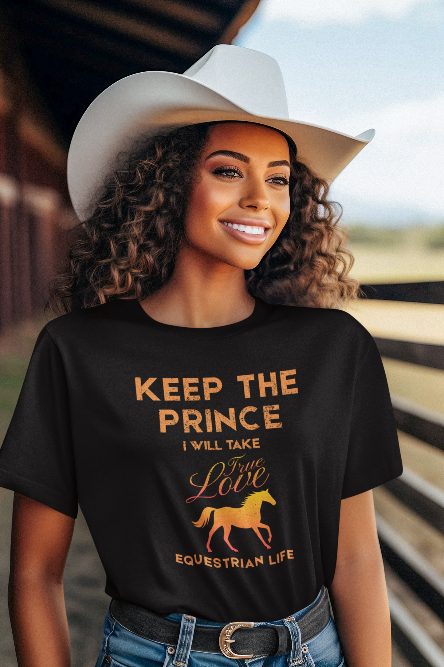 Woman wearing a black t-shirt with equestrian-themed text and graphics, standing in a barn.