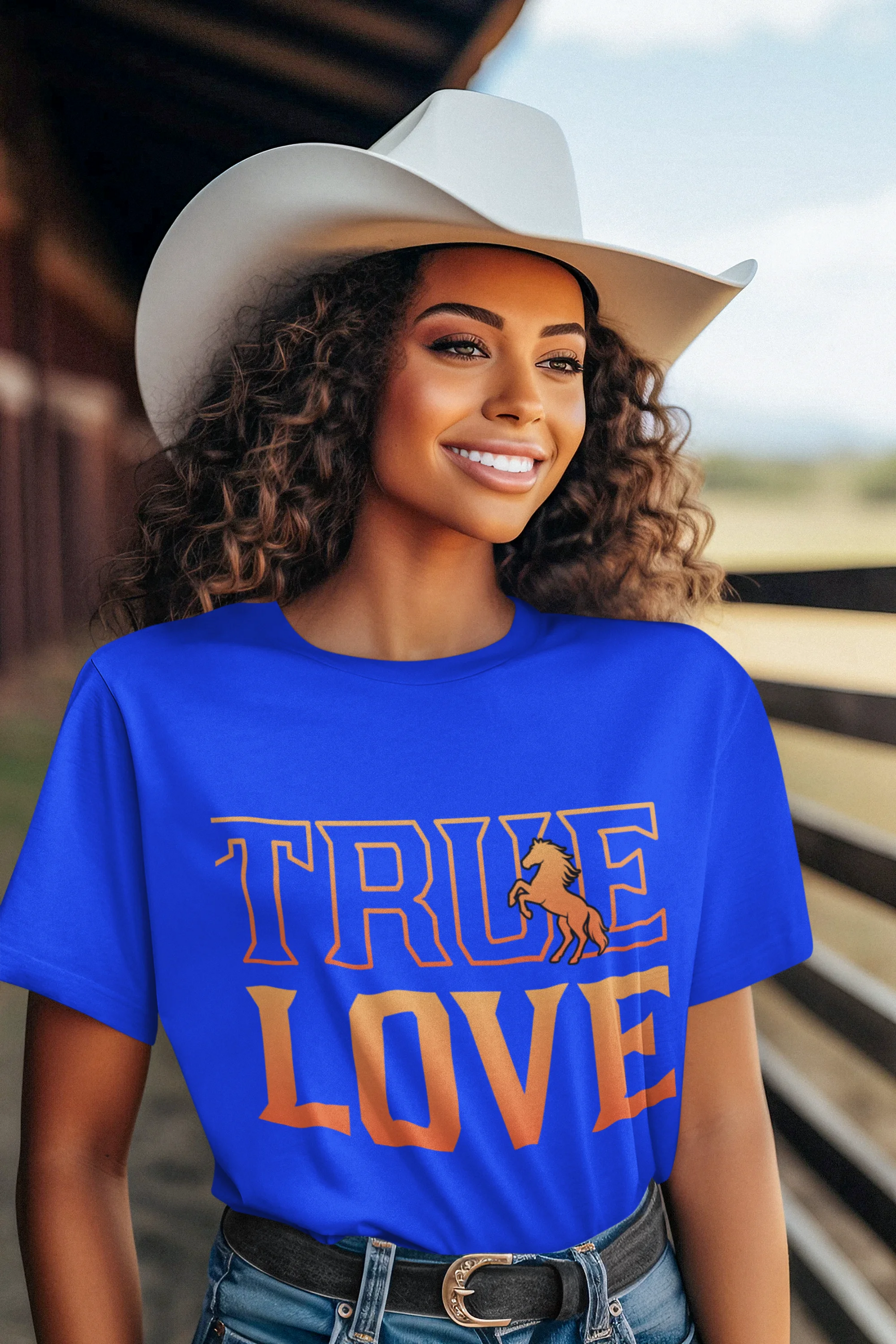 Woman wearing a blue 'TRUE LOVE' t-shirt with a cowboy hat in a rustic setting.