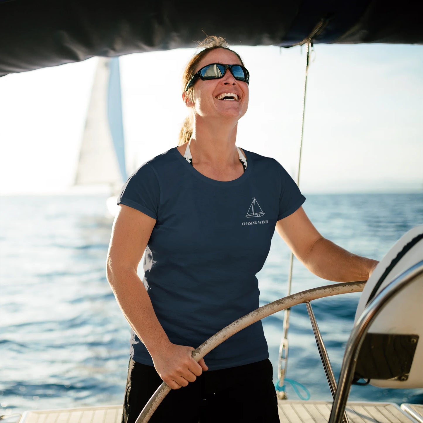 Sailing T-Shirt Woman on a sailboat steering the wheel with a scenic ocean background