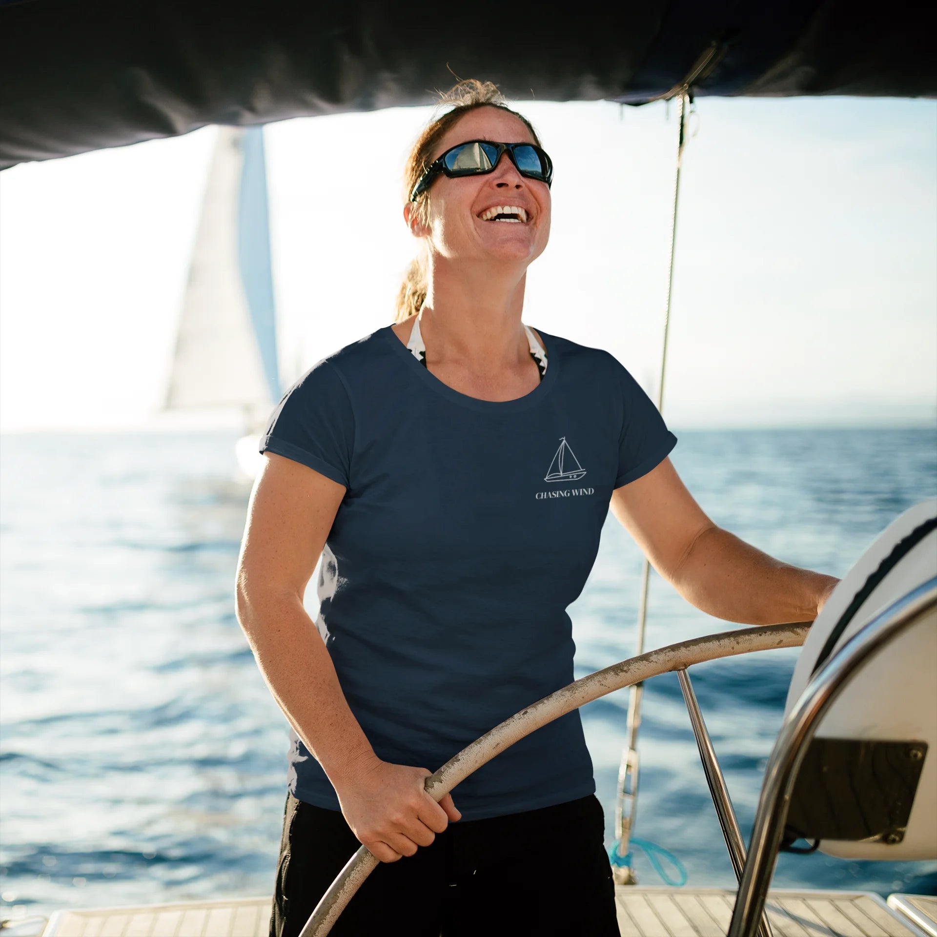 Sailing T-Shirt Woman on a sailboat steering the wheel with a scenic ocean background