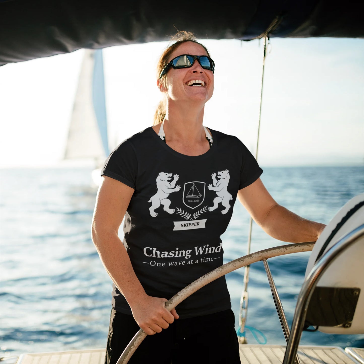 Sailing Boat T Shirt Person on a boat wearing a black t-shirt with a design and text, with water in the background