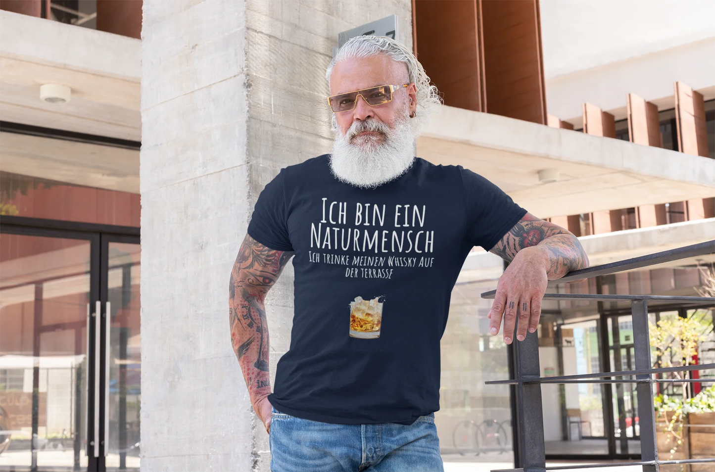 Naturmensch Whisky auf der Terrasse Man wearing a black t-shirt with German text and a beer graphic, standing outdoors.