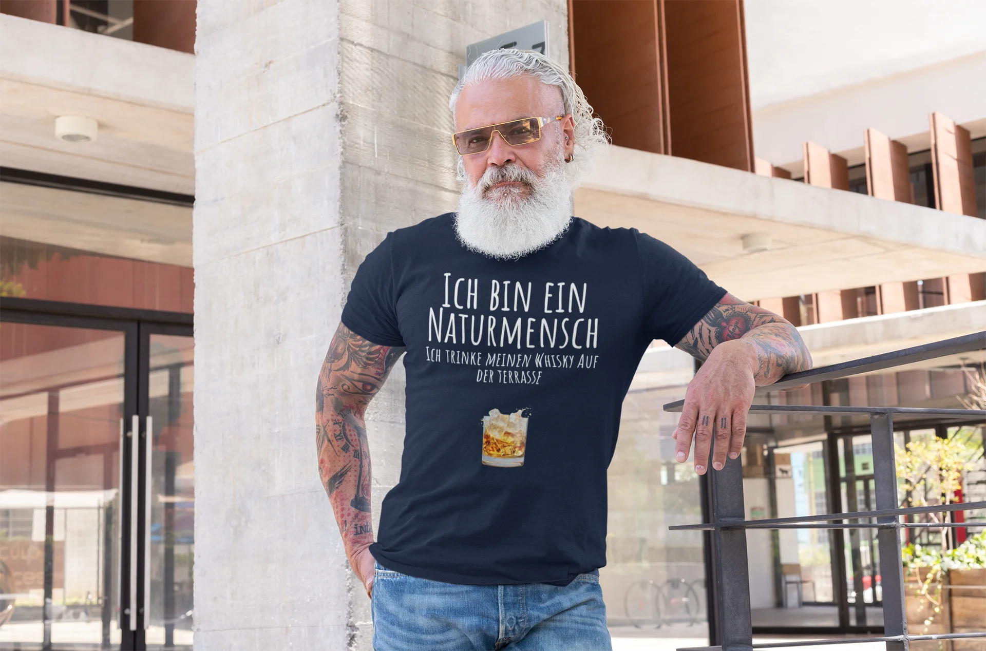 Naturmensch Whisky auf der Terrasse Man wearing a black t-shirt with German text and a beer graphic, standing outdoors.
