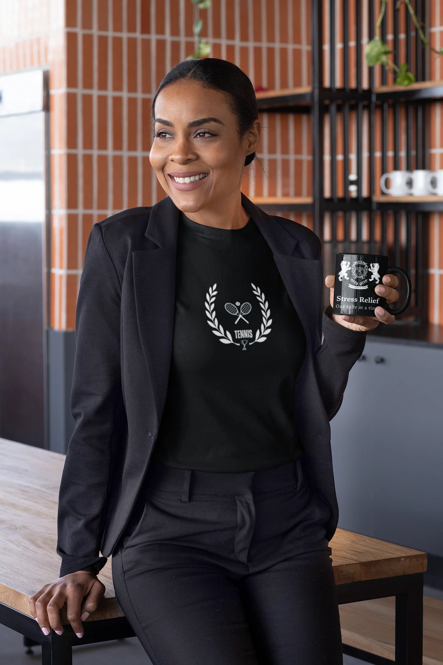 Tennis Mug Woman holding a black mug with a logo in a kitchen setting