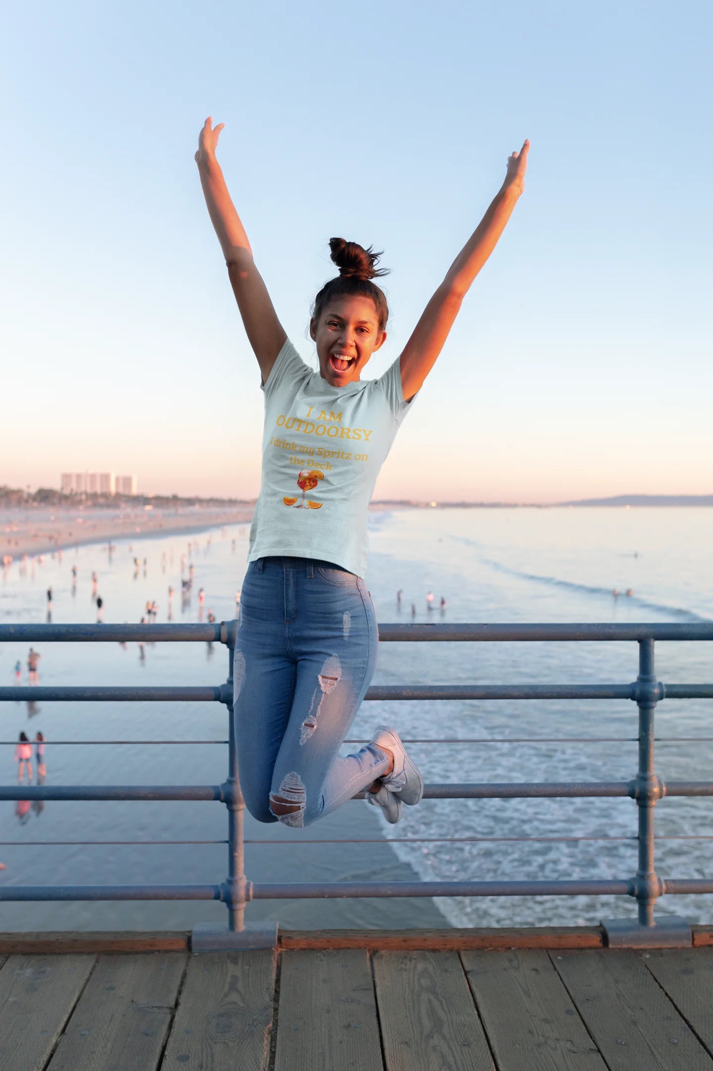 Funny Spritz Shirt Person jumping on a pier with arms outstretched, enjoying a sunny day by the water.