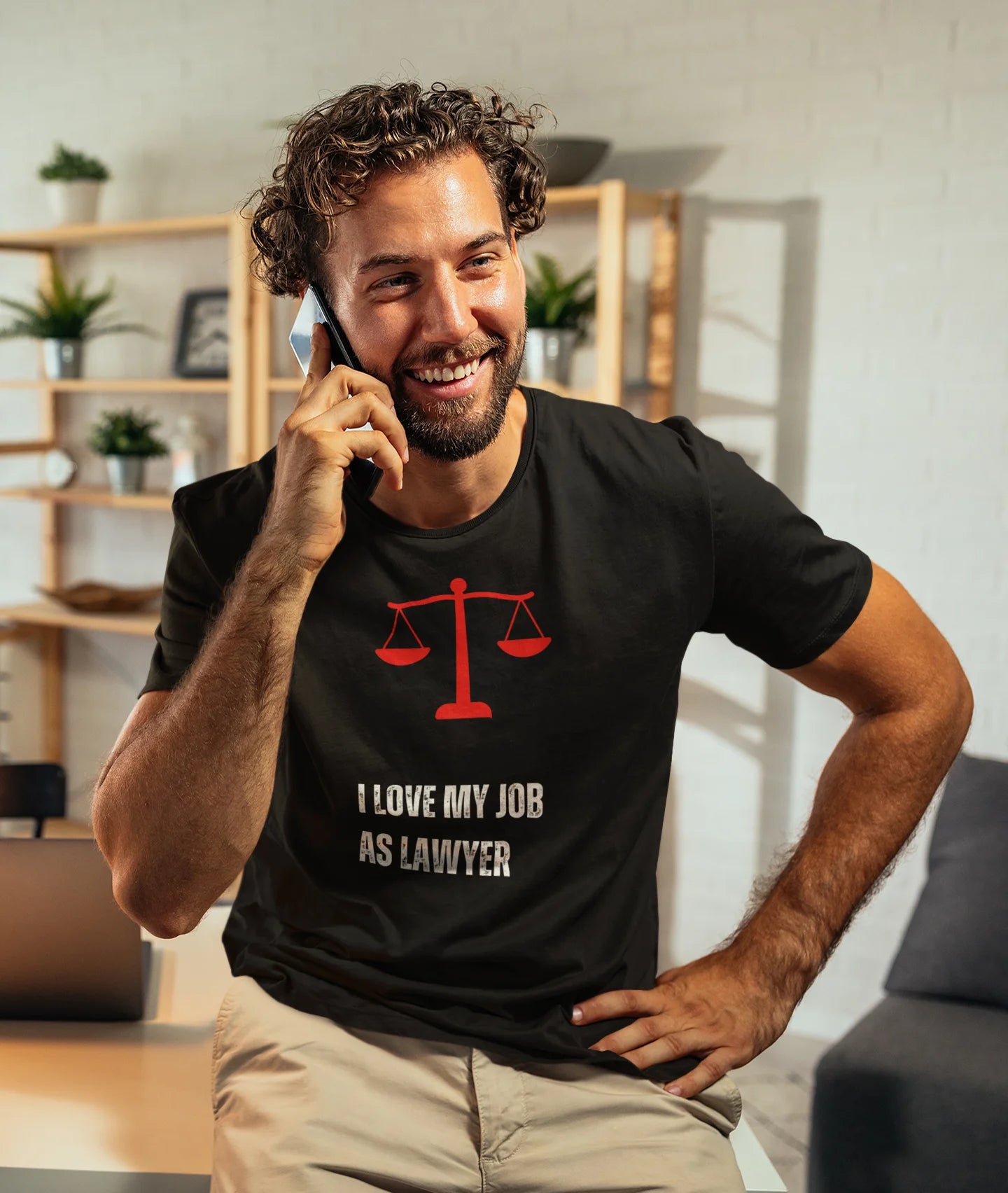 Funny Lawyer Shirt Man wearing a black t-shirt with a red scale design and text, sitting in a room.