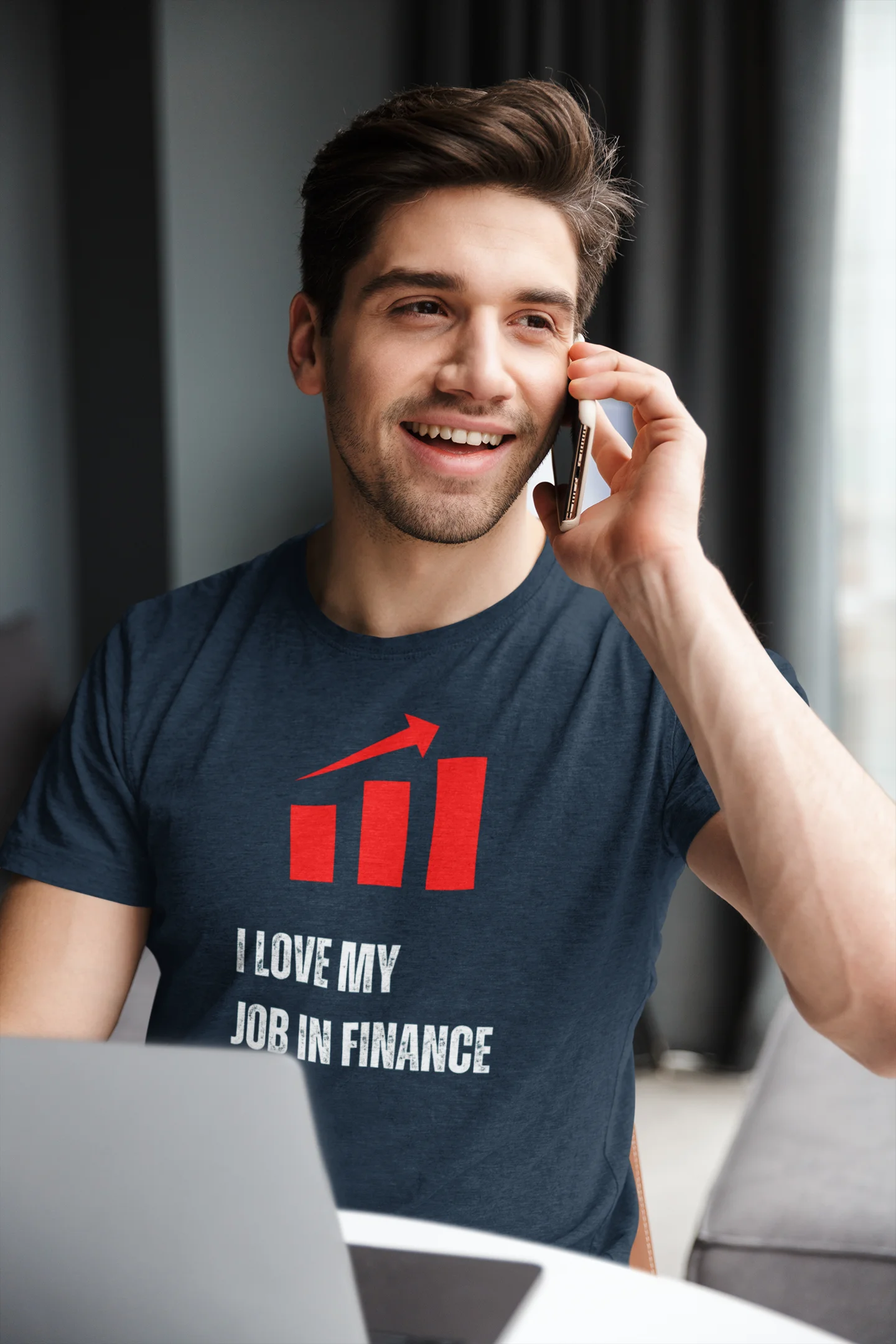 Finance Manager Shirt Man talking on a phone with a laptop, wearing a t-shirt with a graphic and text.