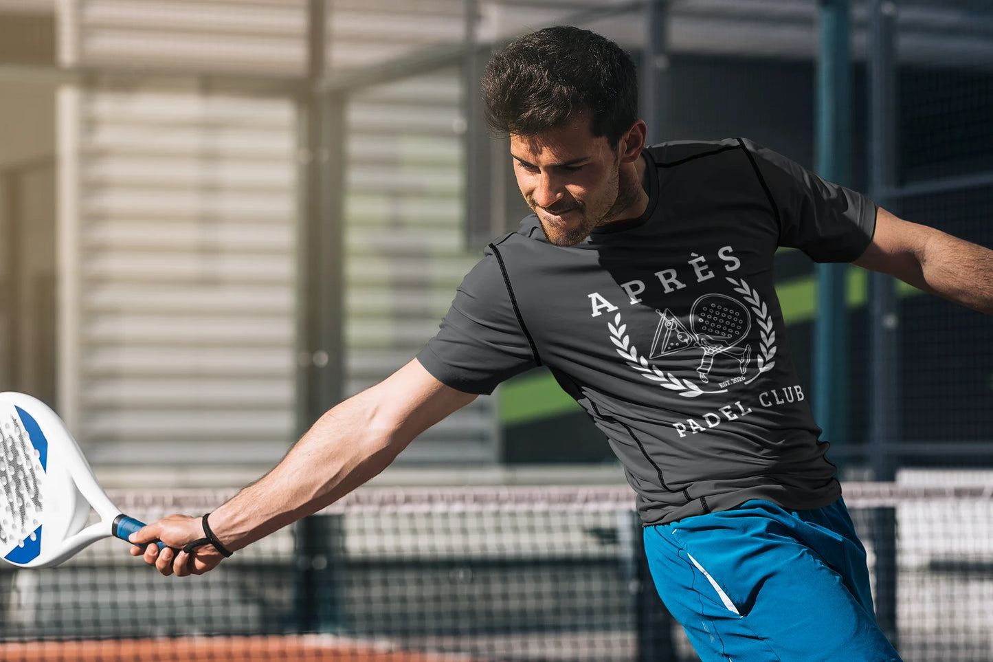Padel Club Shirt Man playing paddle tennis on a court wearing a branded t-shirt.