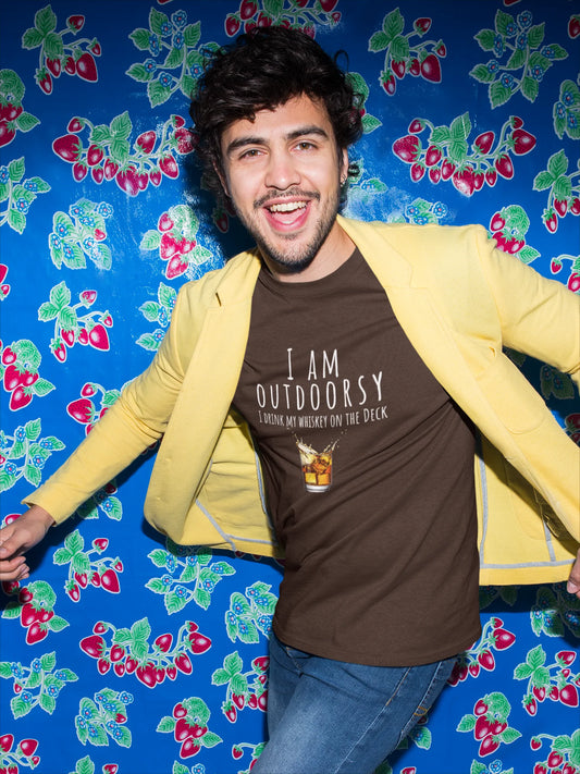 Person wearing a yellow jacket over a brown t-shirt with text, standing against a colorful floral-patterned background.