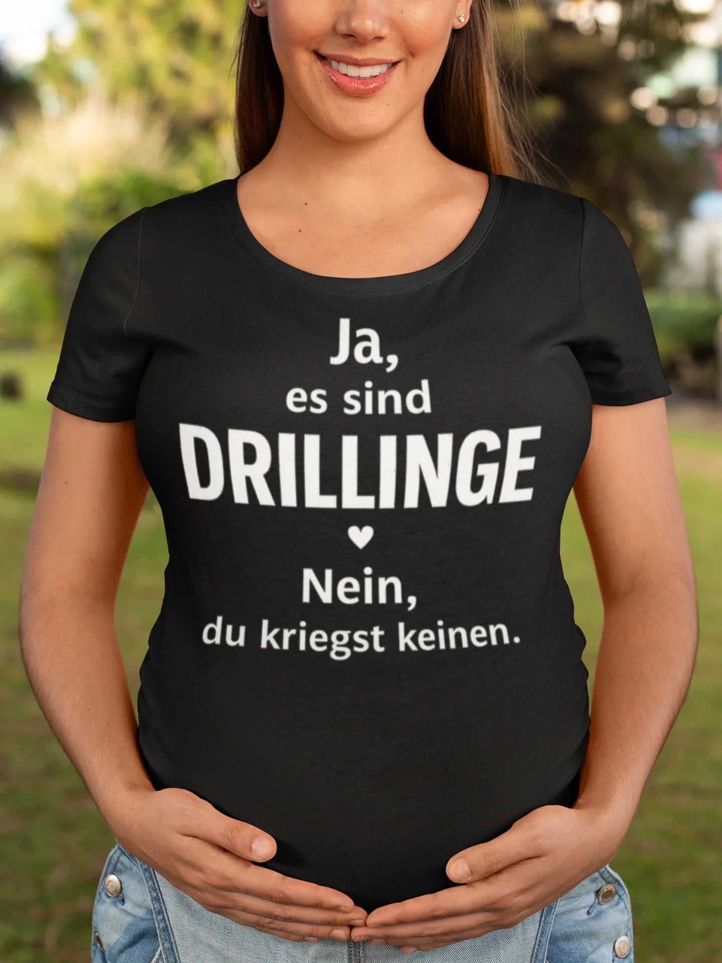 T-Shirt für Drillingseltern Pregnant woman wearing a black t-shirt with German text outdoors.