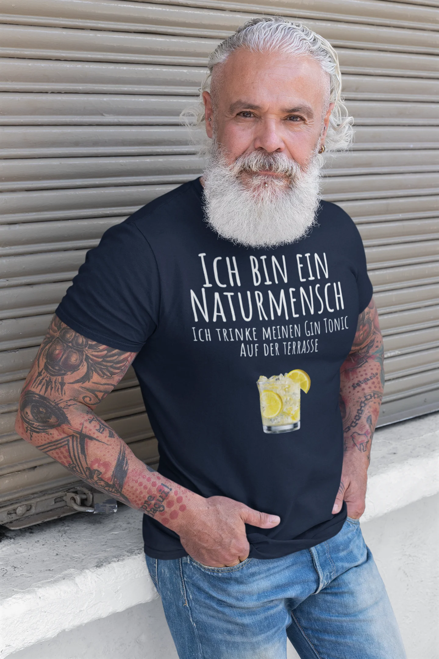 Man wearing a black t-shirt with German text and a lemon graphic, standing in front of a metallic shutter.