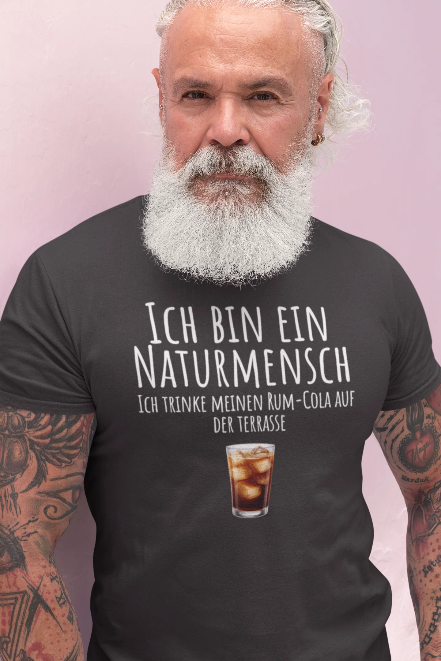 Man wearing a black t-shirt with German text and a drink graphic against a light pink background