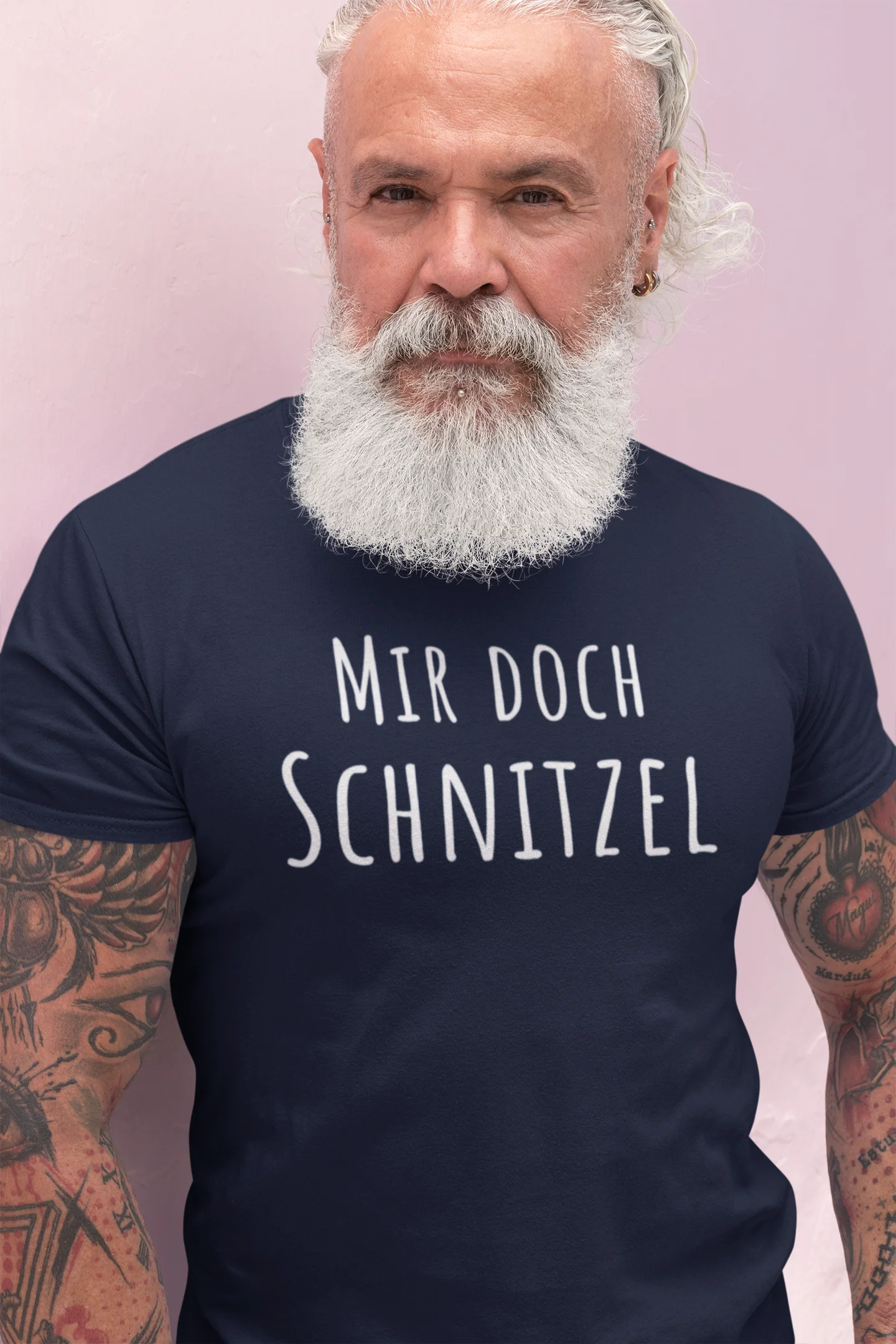 Man wearing a navy blue t-shirt with text, standing against a light pink background