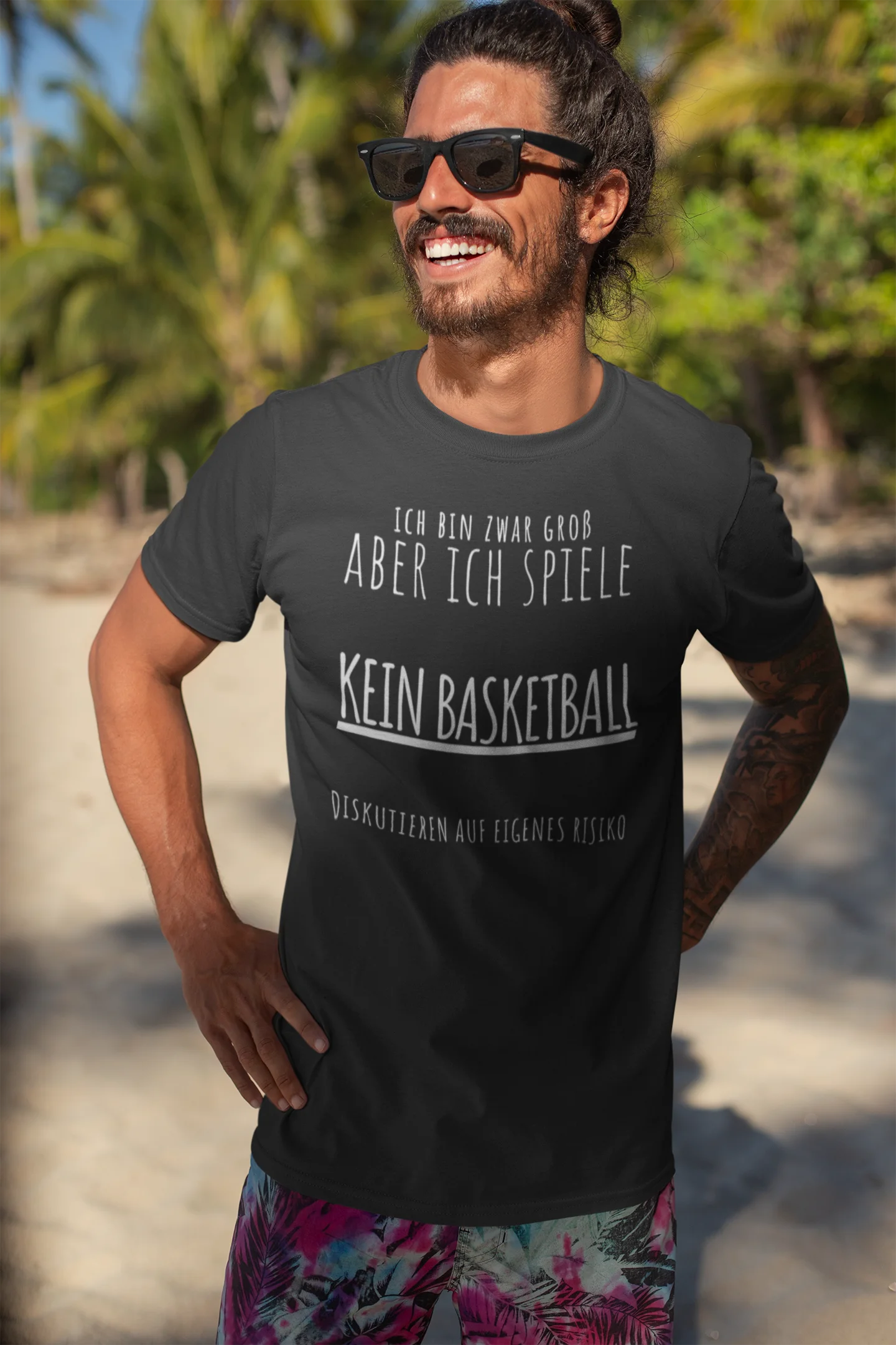 Man wearing a black t-shirt with German text on a beach