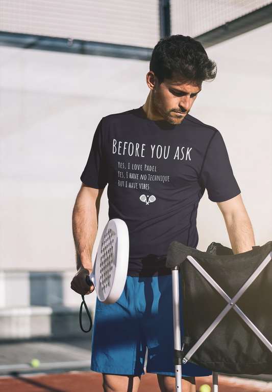 Man holding a pickleball paddle and wearing a t-shirt with text on a tennis court.
