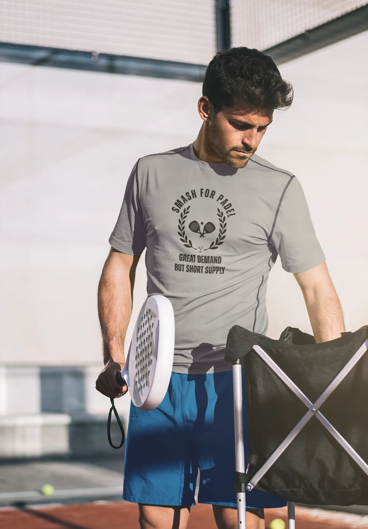 Man holding a paddle and a paddle rack on a tennis court