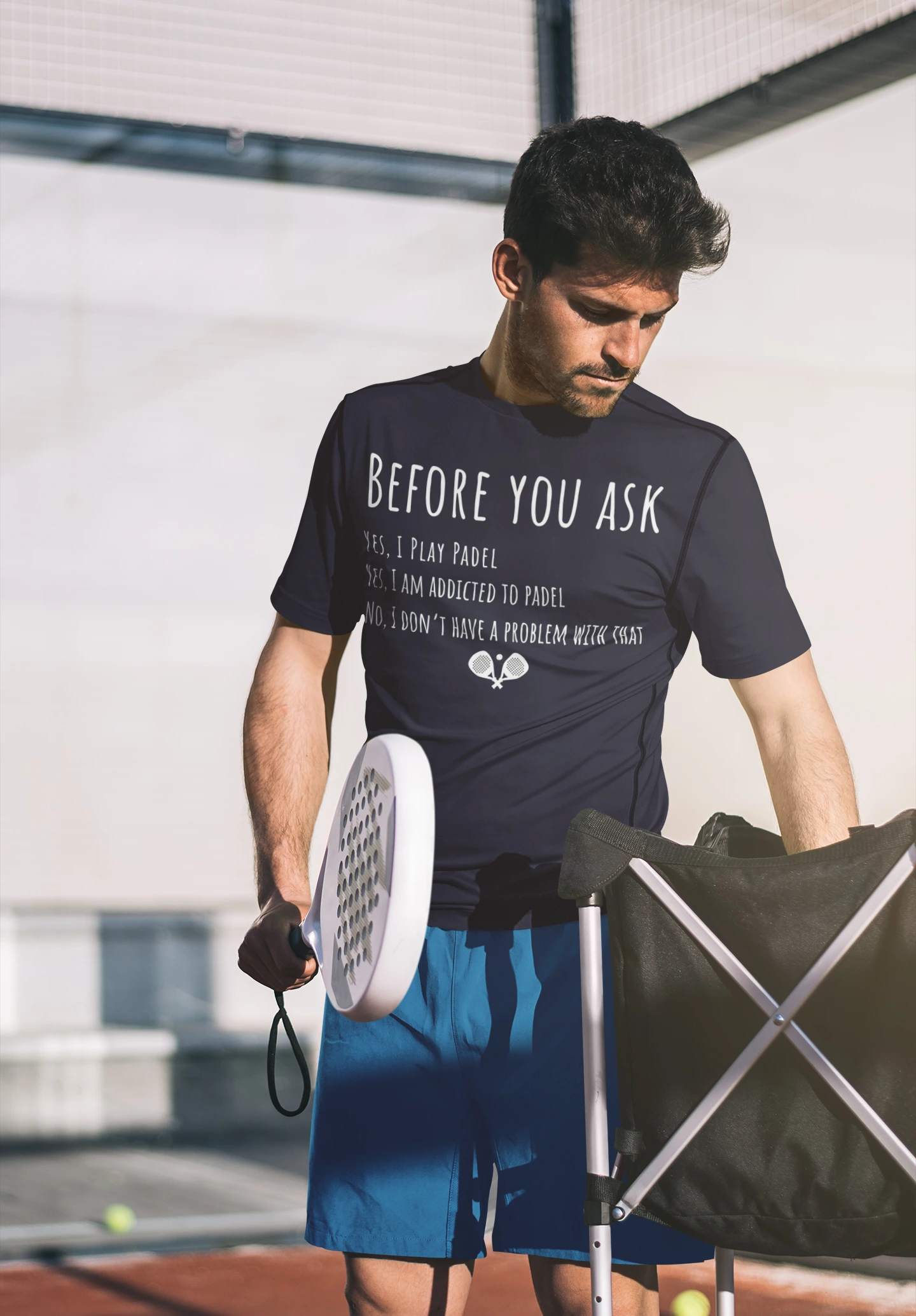 Man holding a tennis racket with a humorous t-shirt on a tennis court