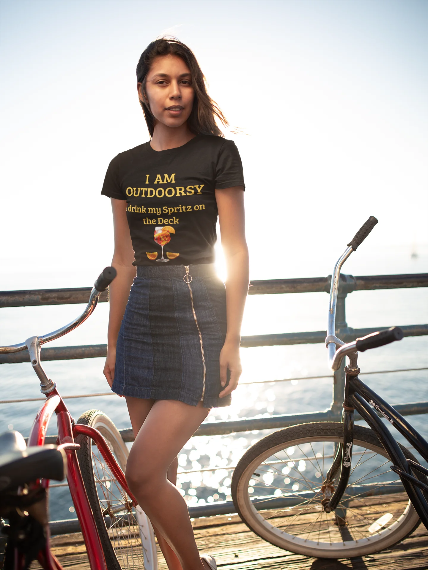 Funny Spritz Shirt Woman wearing a t-shirt with text and graphics, standing on a dock with bicycles.