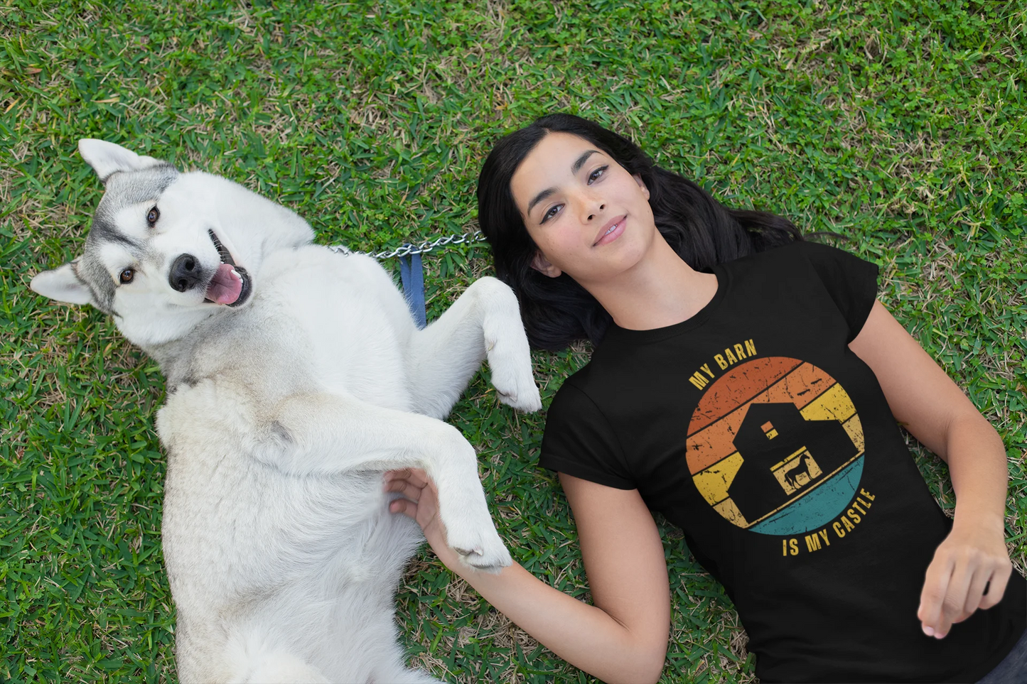 Equestrian Funny Tee Woman lying on grass with a white dog, wearing a black t-shirt with a graphic design.